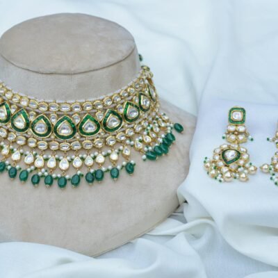 Luxurious gold and green jewelry set featuring intricate beadwork and pearls displayed on a fabric backdrop.